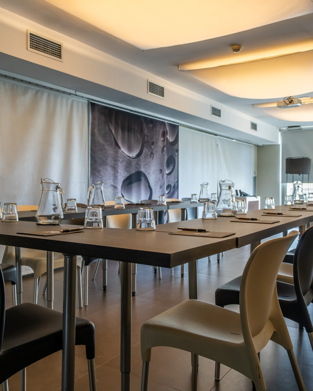 Mesa larga con sillas y vasos de agua en el salón de negocios del Hotel Constanza